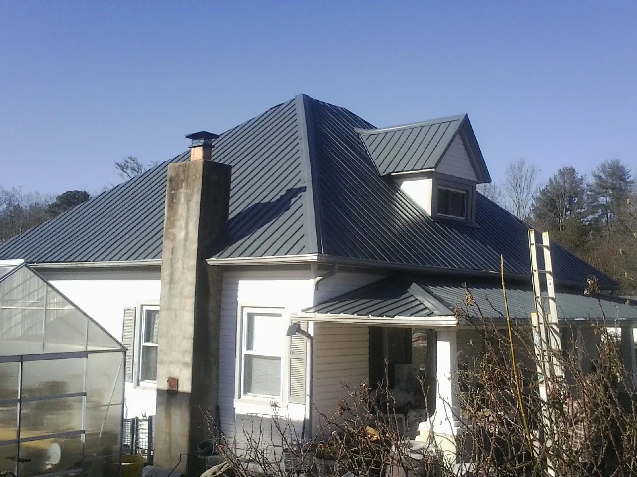 Dark blue standing seam metal roof on a white farmhouse with dormer — Slate & Tile Roof Repair by Roofing Brothers in Pageland
