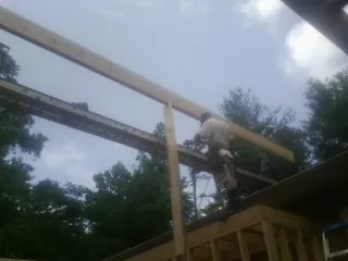 Carpenter setting a ridge beam over a new addition frame — Ice Dam Removal by Roofing Brothers in Pageland