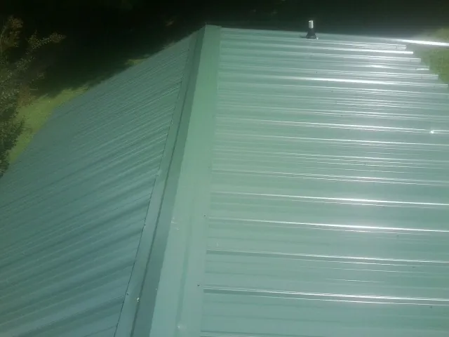 New green metal panels meeting at the ridge of a roof — Flat Roof Repair work by our crew in Pageland