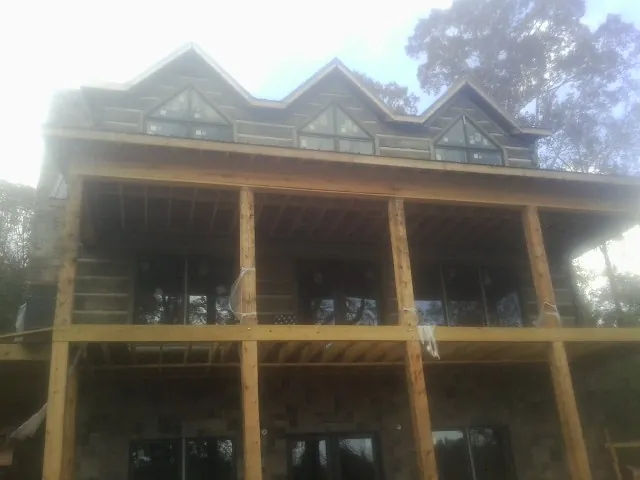 Dormers and porch framing on a large log home under construction — Roof Coating work by our crew in Pageland