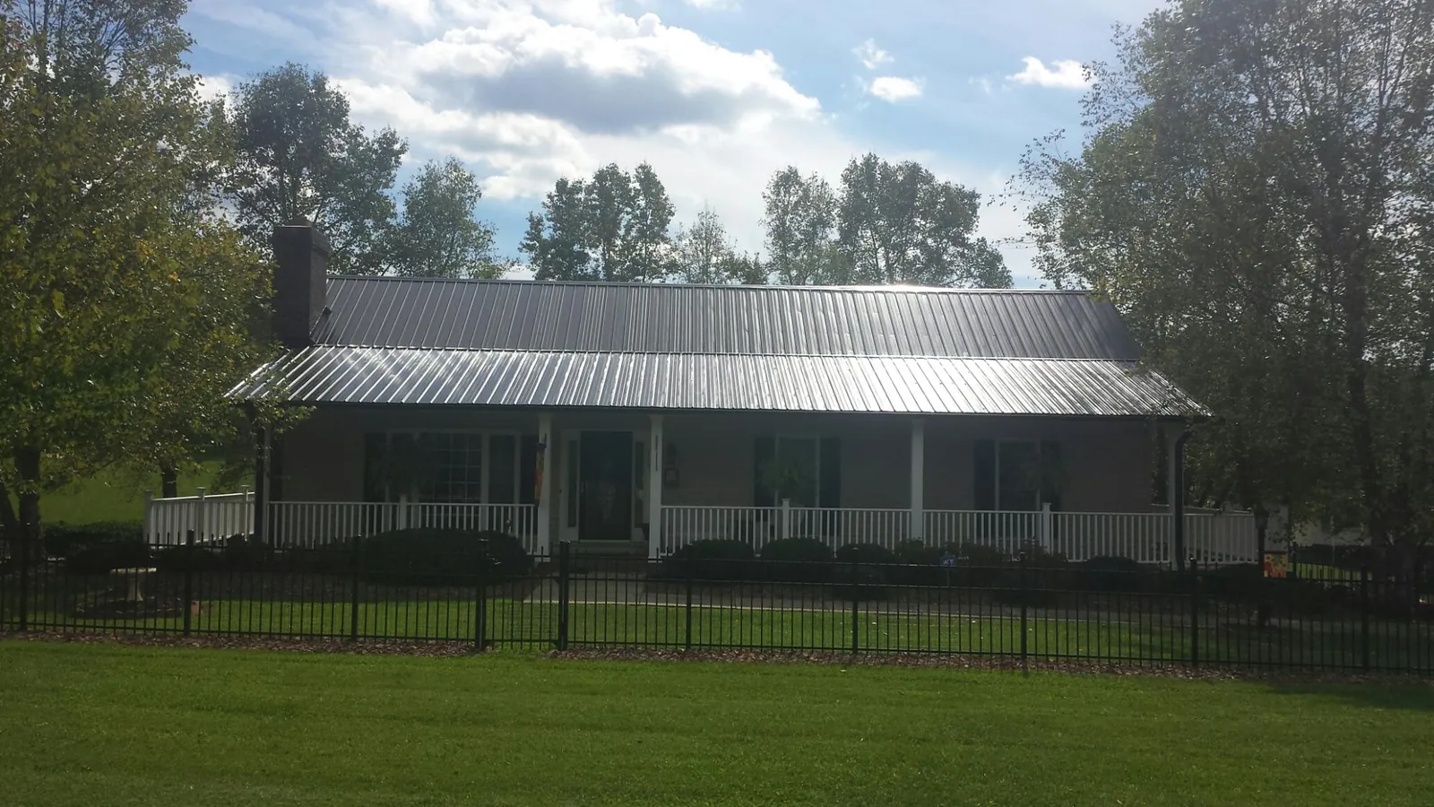 Gray metal roof on a brick ranch with a full width front porch — Gutter Guard Installation work by our crew in Pageland