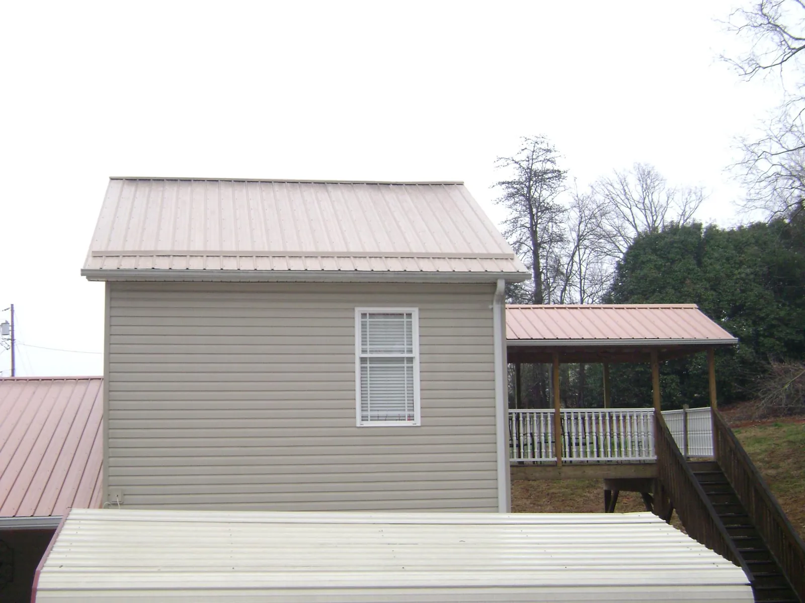 Tan metal roofs on a two story addition and attached porch, from a Roof Replacement job in Pageland