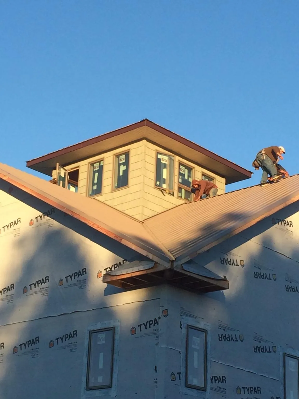 Roofers working around a rooftop cupola on a new metal roof at sunset — Roof Waterproofing in Pageland by Roofing Brothers